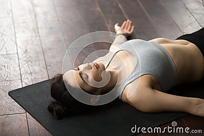 Young attractive woman relaxing in Savasana pose, white loft stu Stock Photo