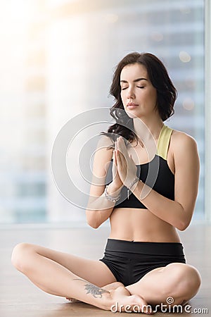 Young attractive woman in Sukhasana pose against sunny floor win Stock Photo