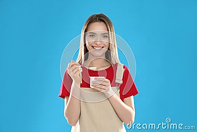 Young attractive woman with tasty yogurt on background Stock Photo