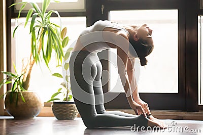 Young attractive woman in Ustrasana pose, home interior backgrou Stock Photo