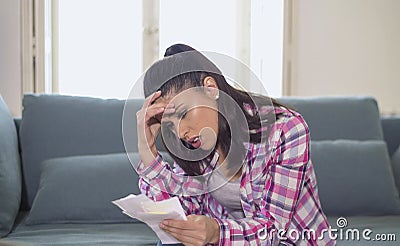 Young attractive and worried hispanic woman checking bills bank papers expenses and monthly payments in stress at apartment living Stock Photo