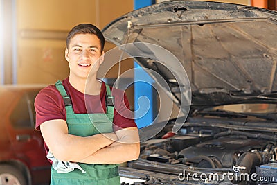 Young auto mechanic near car in service center Stock Photo