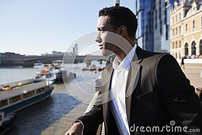 Young back businessman standing at the Thames riverside in the city of London admiring the view, close up Stock Photo