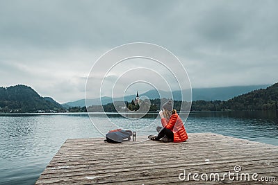 Young backpacker woman sitting and drinking coffee by mountain lake Stock Photo