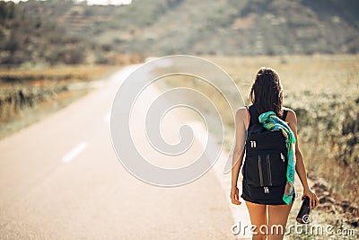 Young backpacking adventurous woman hitchhiking on the road.Traveling backpacks volume,packing essentials.Travel lifestyle Stock Photo