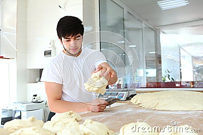 A young Baker puts a portion of dough on the table. The process of making tortillas. Hands and dough are out of focus. Yeast dough Stock Photo