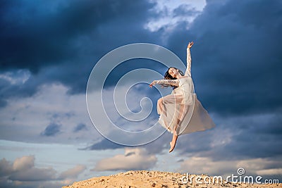 Young ballerina in a light long white dress flies in a jump Stock Photo