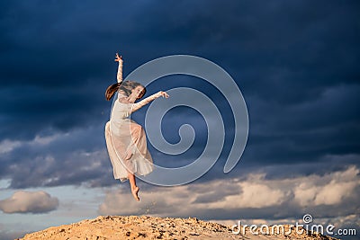 Young ballerina in a light long white dress flies in a jump Stock Photo