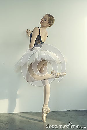 young ballerina in a tutu and pointe shoes standing against the wall posing ballet elements Stock Photo