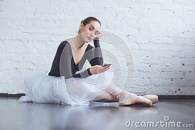 Young ballet dancer sitting leaning white wall using phone in studio active lifestyle Stock Photo