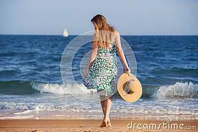 Young barefoot woman with hat walking on ocean beach at sunny hot day Stock Photo