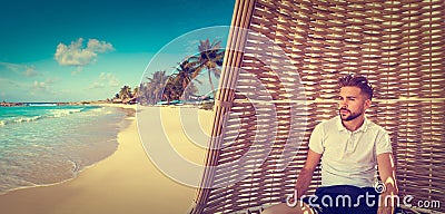 Young beard man in parasol at tropical beach Stock Photo