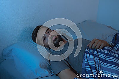 Young beard man lying on the bed awake Stock Photo