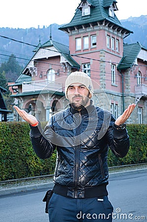 Young bearded handsome man sending kisses on background of Beautiful old pink house in the mountain Stock Photo