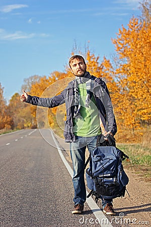 Young bearded hipster hitchhiker with backpack try to catch car Stock Photo