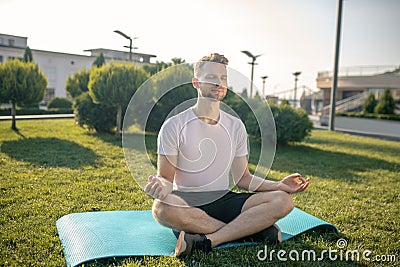 Young bearded male sitting in lotus pose outside, hands in Gyan mudra Stock Photo