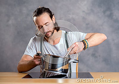 Young bearded man with cooking pot and egg whish Stock Photo