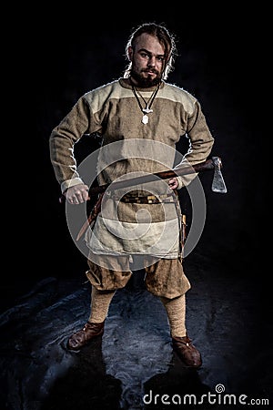 Young bearded man in a viking age clothing holding a battle ax Stock Photo