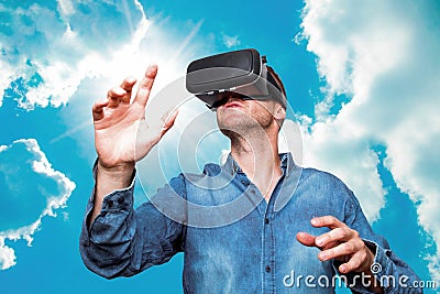 Young bearded man wearing virtual reality glasses in modern interior design coworking studio. Smartphone using with VR goggles he Stock Photo