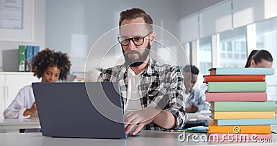 Young bearded sitting at desk and using laptop in classroom Stock Photo