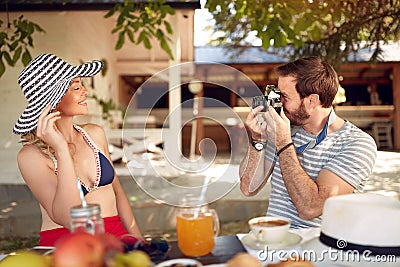 Young beardy male taking photo of attractive blonde with old photo camera Stock Photo