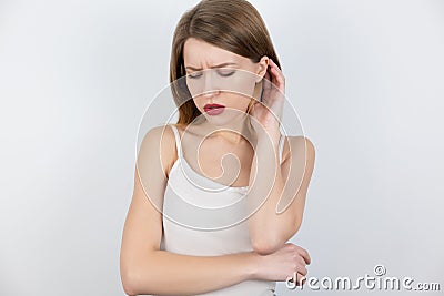Young beatuiful blond woman looks upset standing alone on isolated white background, melancholic mood Stock Photo