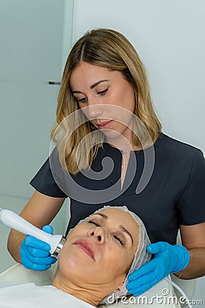 esthetician performs relaxing treatment on the cheekbone of a woman Stock Photo