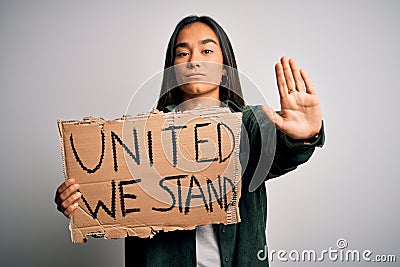 Young beautiful activist asian woman asking unity holding banner with united stand message with open hand doing stop sign with Stock Photo