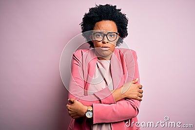 Young beautiful African American afro businesswoman with curly hair wearing pink jacket shaking and freezing for winter cold with Stock Photo