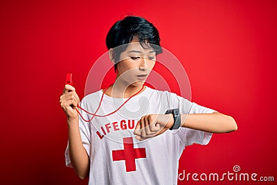 Young beautiful asian lifeguard girl wearing t-shirt with red cross using whistle Looking at the watch time worried, afraid of Editorial Stock Photo