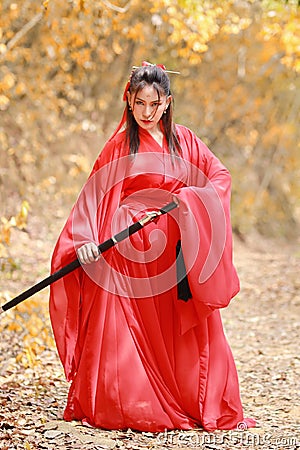 Young beautiful asian woman dress in traditional Chinese old fashion warrior style with ancient word and umbrella. Cute girl in re Stock Photo