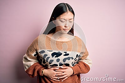 Young beautiful asian woman wearing animal print fashion sweater over pink isolated background with hand on stomach because Editorial Stock Photo