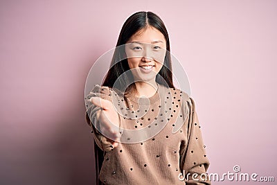 Young beautiful asian woman wearing fashion and elegant sweater over pink solated background smiling cheerful offering palm hand Editorial Stock Photo