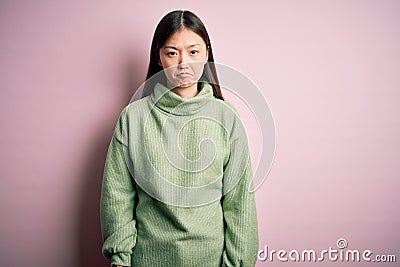 Young beautiful asian woman wearing green winter sweater over pink solated background depressed and worry for distress, crying Editorial Stock Photo