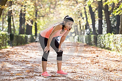 Attractive sport woman in runner sportswear breathing gasping and taking a break tired and exhausted after running workout on Autu Stock Photo