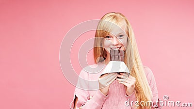 Young beautiful blonde with chocolate. teen girl bites chocolate. the temptation to eat forbidden chocolate. cheerful positive Stock Photo