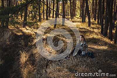 Young beautiful blonde girl with curly hair sitting on the ground in peaceful autumn forest - calm and meditative Stock Photo