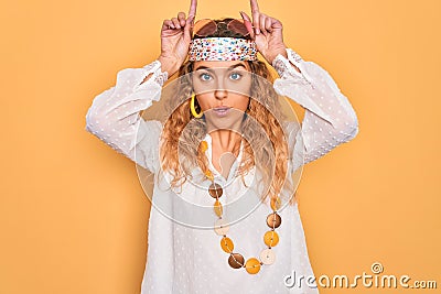 Young beautiful blonde hippie woman with blue eyes wearing sunglasses and accessories doing funny gesture with finger over head as Stock Photo