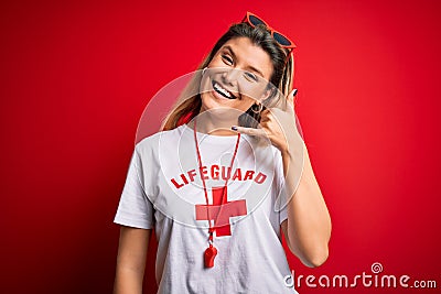 Young beautiful blonde lifeguard woman wearing t-shirt with red cross and whistle smiling doing phone gesture with hand and Editorial Stock Photo