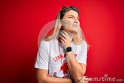 Young beautiful blonde lifeguard woman wearing t-shirt with red cross and whistle Touching painful neck, sore throat for flu, clod Editorial Stock Photo