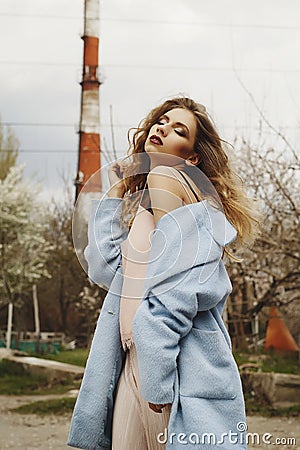 Young beautiful blonde woman posing in blue coat outdoors Stock Photo