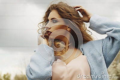 Young beautiful blonde woman posing in blue coat outdoors Stock Photo