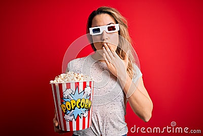 Young beautiful blonde woman watching movie using 3d glasses eating popcorn snack cover mouth with hand shocked with shame for Stock Photo