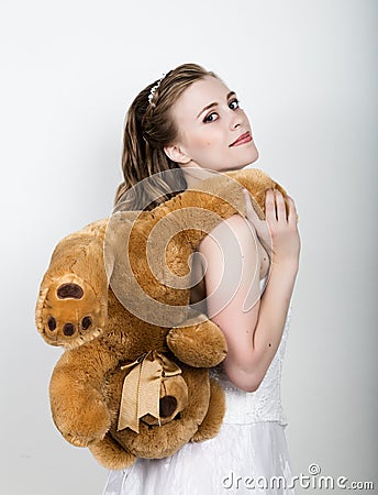 Young beautiful bride holding a teddy bear, they gently hug Stock Photo
