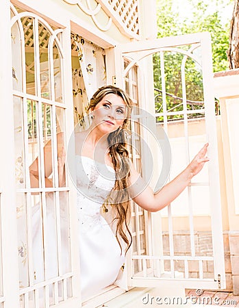 Young beautiful bride waits for groom near the window. Beautiful Bride lit by sunlight. beautiful young bride waiting Stock Photo