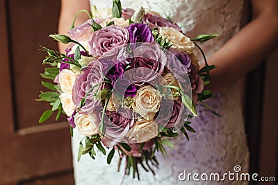 Young beautiful bride in white dress holding wedding bouquet, bouquet of bride from rose cream spray, rose bush, rose purple Memor Stock Photo