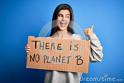 Young beautiful brunette activist woman holding banner protesting to care the planet pointing and showing with thumb up to the Stock Photo