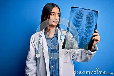Young beautiful brunette doctor woman wearing stethoscope holding chest xray with a confident expression on smart face thinking Stock Photo