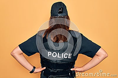 Young beautiful brunette policewoman wearing police uniform bulletproof and cap standing backwards looking away with arms on body Stock Photo