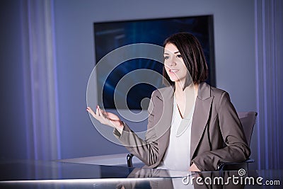 Young beautiful brunette television announcer at studio during live broadcasting.Female TV director at editor in studio. Stock Photo